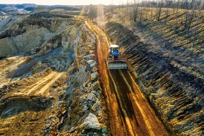 High-angle shot of a bulldozer on a rocky quarry path in Rochester, MN, during daytime.