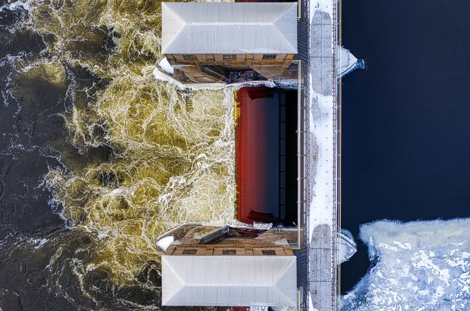 Aerial shot of a dam with frozen river and turbulent waters in winter. Captured in Minnesota.