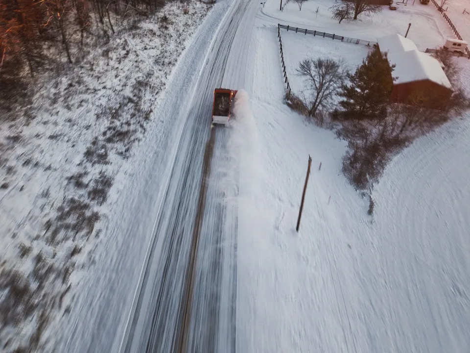 Aerial view of a snowplow clearing a rural road surrounded by snow in Kellogg, Minnesota.