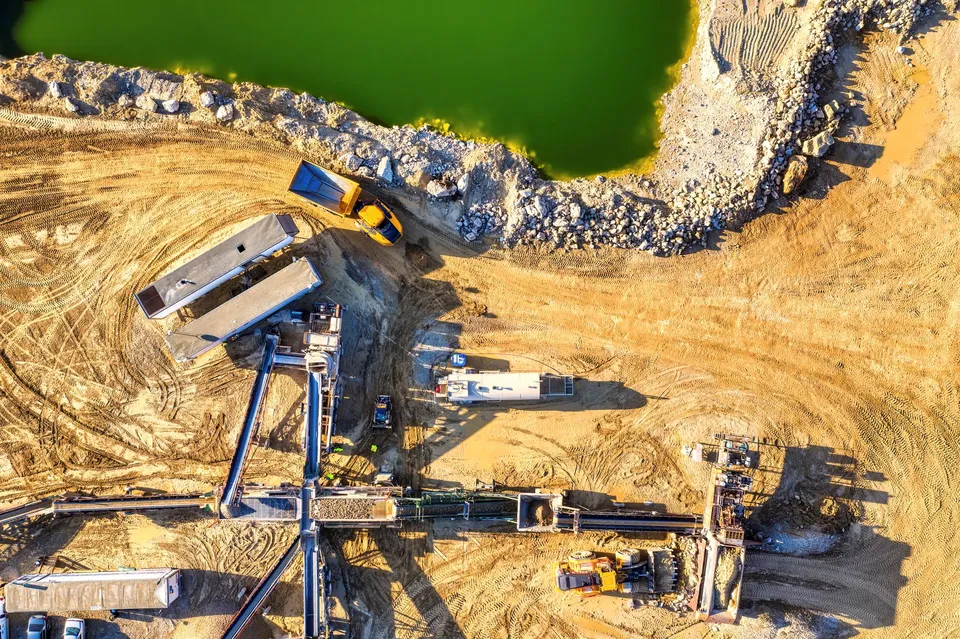 High-resolution aerial image of construction site with heavy machinery and a green water body in Rochester, MN.